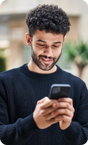 Newcastle Specialist Prosthodontics Smiling man looking at his phone in an outdoor setting.